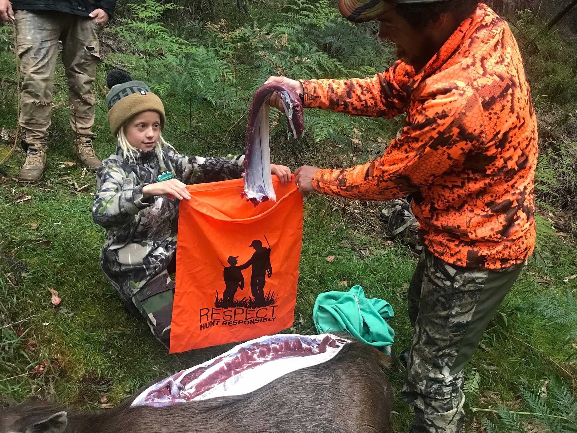 A man puts a fillet of deer meat into a bag held open by a girl.